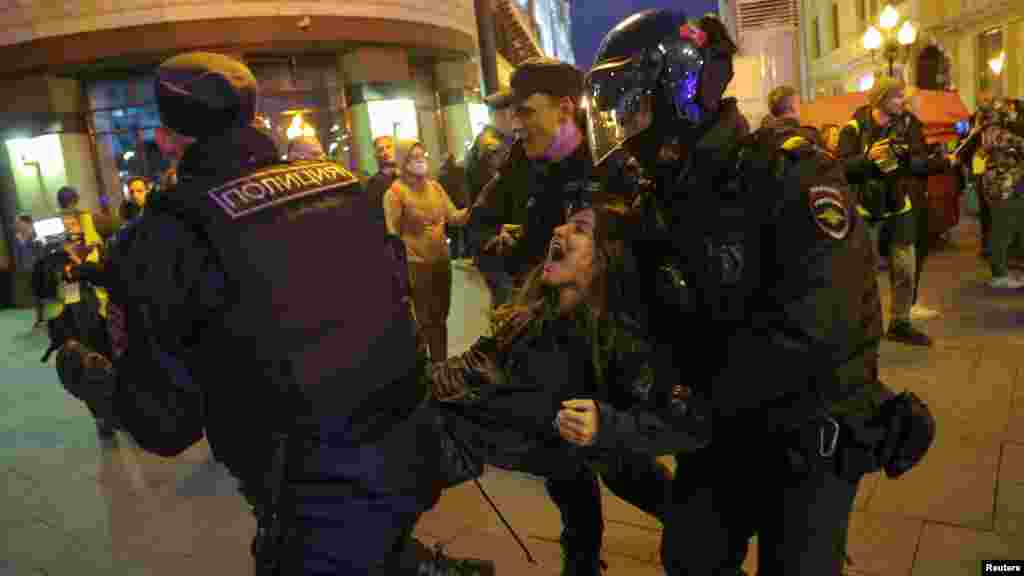Egy fiatal nő kiabál, miközben a rendőrök a végtagjainál fogva elhurcolják