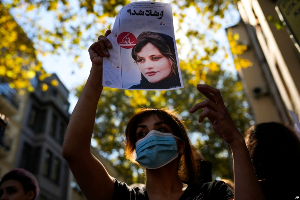 A woman raises a newspaper article reading in Persian "It was Ershad?" the term for Iran's morality police, during a protest outside Iran's general consulate in Istanbul.