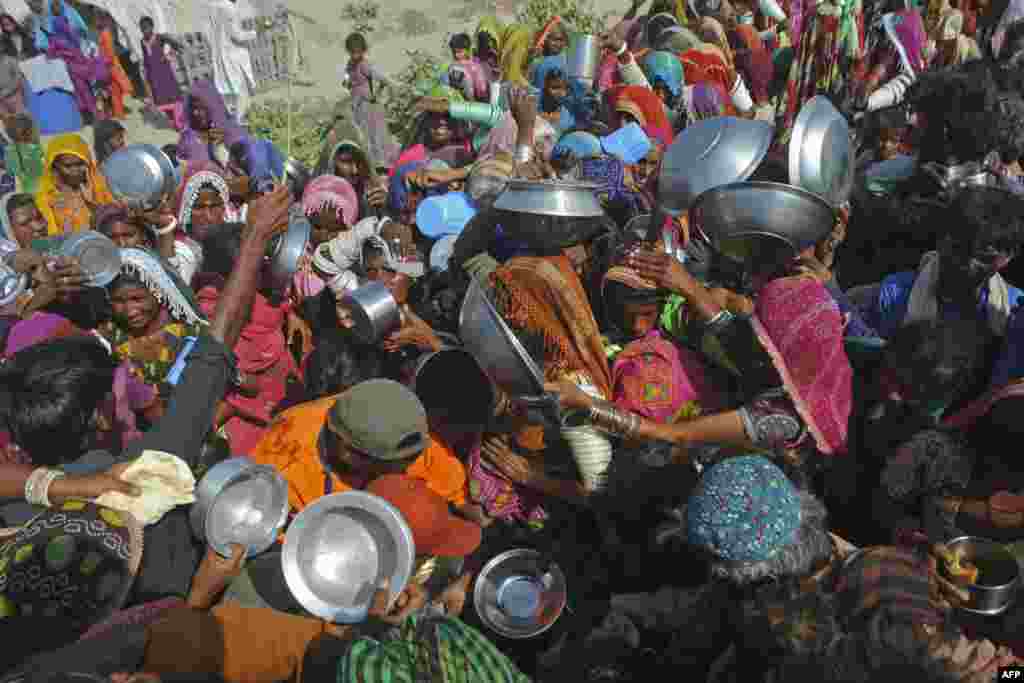 Internally displaced people gather to receive free food near their makeshift camp in Pakistan&#39;s flood-hit Sindh Province.