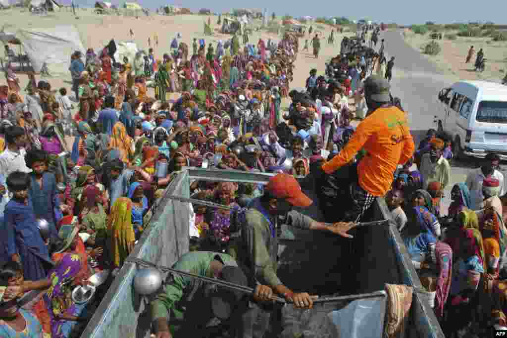 Internally displaced people gather to receive food handouts near a camp in flood-hit Sindh Province on September 19. More than 1,500 people have been killed as a result of the floods, including a growing number from disease.