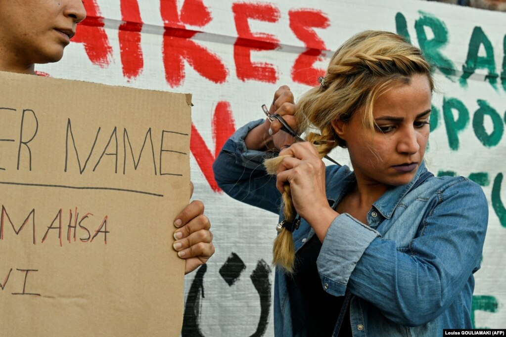 Një grua refugjate iraniane që jeton në Greqi duke prerë flokët gjatë një demonstrate në Athinë, më 24 shtator 2022,