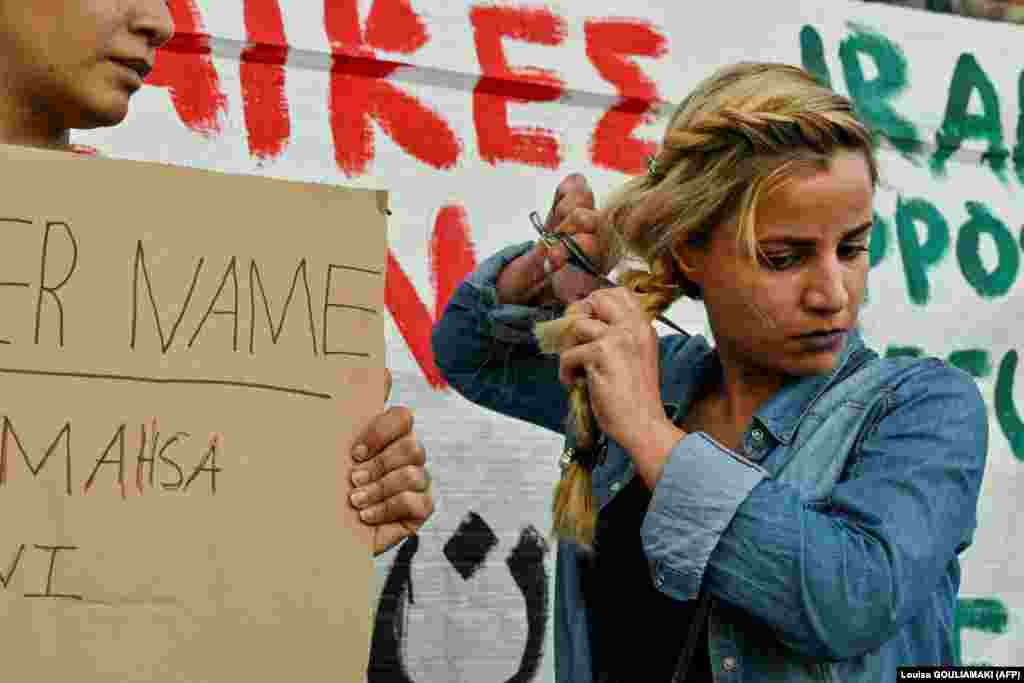Egy iráni menekült nő tiltakozásul levágja a haját a Görögországban élő irániak tüntetésén, Athén központjában 2022. szeptember 24-én