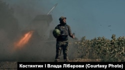 Украински войник държи диня, докато на заден план се вижда стрелящ гранатомет.