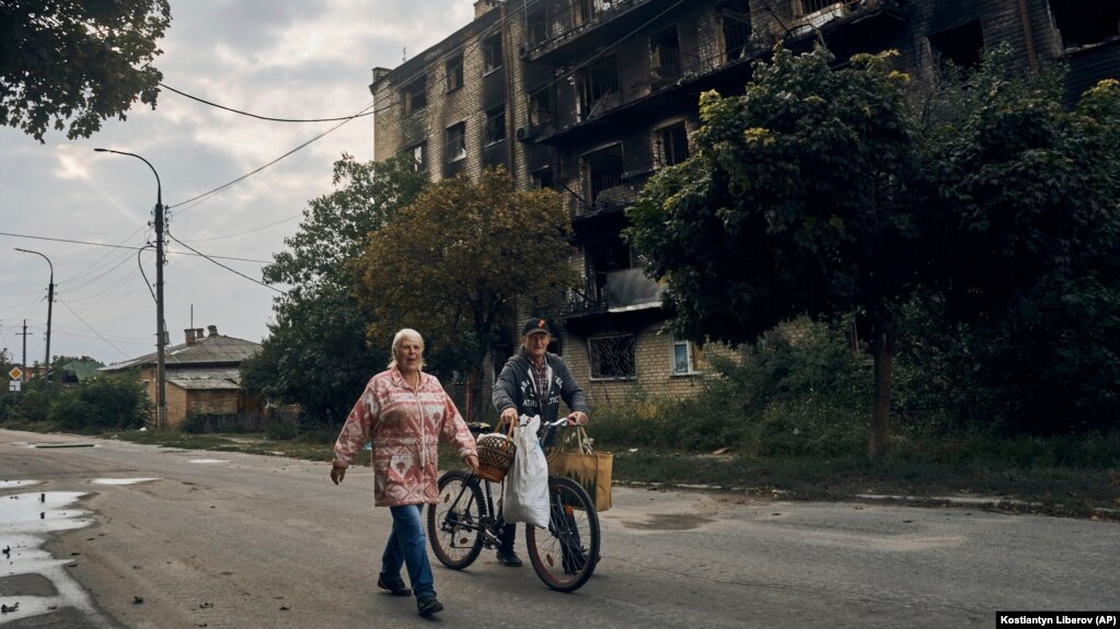 Жители на Изюм минават покрай бомбардирана сграда. 13 септември 2022.