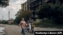 Жители на Изюм минават покрай бомбардирана сграда. 13 септември 2022.