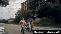 Residents walk past a war-damaged building in the center of the recently liberated town of Izyum in Ukraine's Kharkiv region on September 13. 