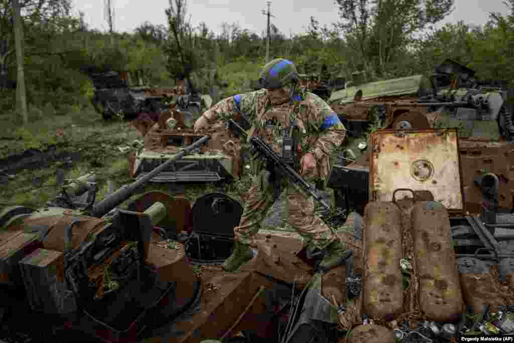 Iuri Usati, un militar al Gărzii Naționale Ucrainene, merge pe APC-urile rusești distruse la punctul de control din apropierea zonei recent recucerite din Izium.&nbsp;Fotografie din 15 septembrie 2022.&nbsp;