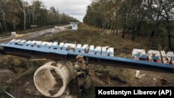 Украинский военный на фоне российского знака "Купянский район". 2022 год