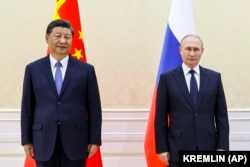Председатель Китая Си Цзиньпин (слева) и президент России Владимир Путин позируют фотографу в кулуарах саммита Шанхайской организации сотрудничества (ШОС) в Самарканде. Узбекистан, 15 сентября 2022 года.