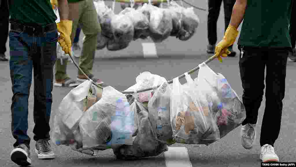 Önkéntesek szállítják el a szemetet műanyag szatyrokban a World Cleanup Day keretében megrendezett szemétszedés végén Kambodzsa fővárosában 2022. szeptember 17-én