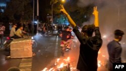 A demonstrator raises his arms and makes the victory sign during a protest for Mahsa Amini in Tehran on September 19.