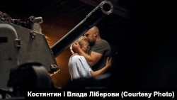 A Ukrainian soldier hugs his bride in front of a howitzer barrel.