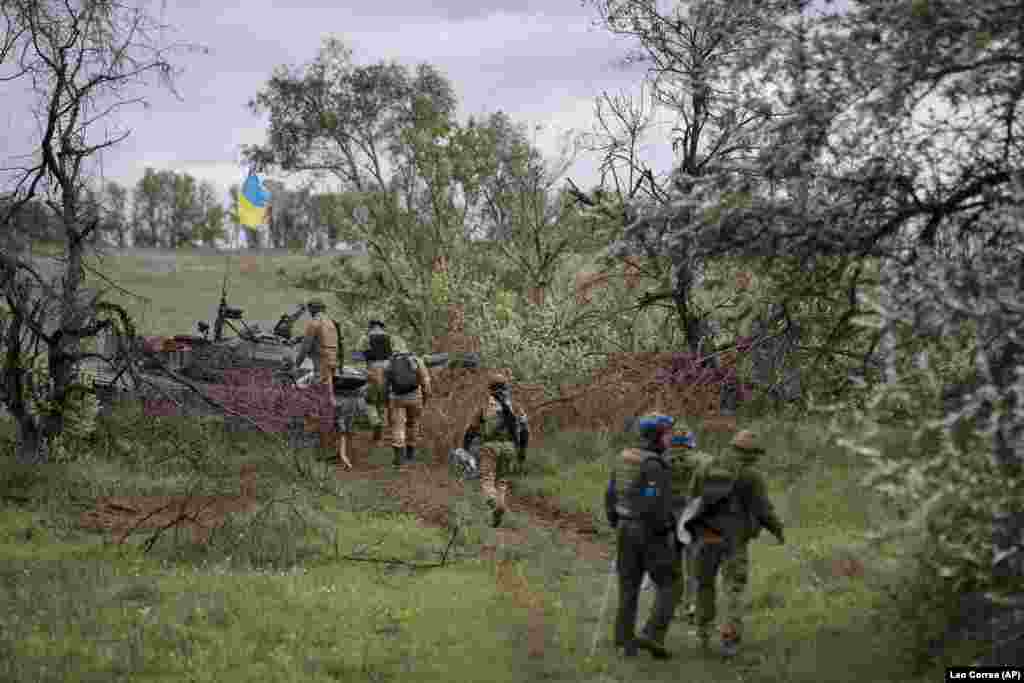 National Guardsmen approach a damaged Russian tank that has been fitted with a Ukrainian flag during the recovery operation.&nbsp;