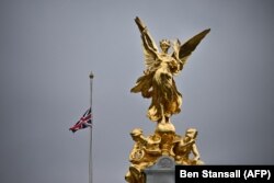 Flamuri i Britanisë në gjysmë-shtizë. Kjo fotografi është realizuar në Pallatin Bakingam, ku gjendet edhe statuja e Mbretëreshës Victoria.