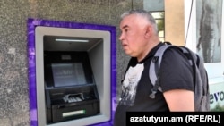 Armenia - Russian national Artur Asafyev tries to retrieve cash from an ATM machine in Yerevan, September 23, 2022