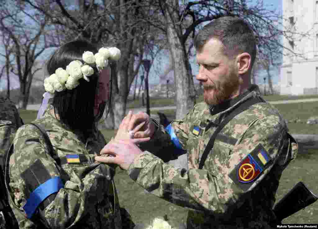 Az Ukrán Területi Védelmi Erők tagjai, Anasztaszija (24) és Vjacseszlav (43) esküvői szertartásukon Kijevben