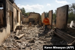 Firefighters walk in the ruins of a building in Sotk that was reportedly hit by shelling.