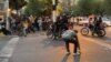 An Iranian police officer raises a baton to disperse demonstrators during a protest in Tehran on September 19 following the death in custody of 22-year-old Mahsa Amini, who was detained by the morality police three days earlier.