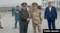 Kyrgyz and Tajik security chiefs Kamchybek Tashiev (left) and Saimumin Yatimov shake hands at the Guliston-Avtodorozhny border crossing on September 19.