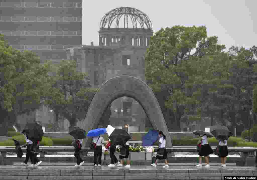 Posetioci drže kišobrane pod jakom kišom i vjetrom izazvanih tajfunom Nanmadol dok se kupola od atomske bombe vidi u pozadini u Memorijalnom parku mira u Hirošimi, zapadni Japan, 19. septembra 2022.