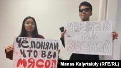 Студенты Карагоз Касым и Айсултан Кудайберген в международном аэропорту Алматы с плакатами для проведения акции против массового приезда россиян. 23 сентября 2022 года 