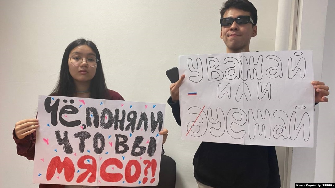 Qarakoz Qasym (left) and Aisultan Qudaibergen were detained at Almaty airport while holding posters saying: "Did you realize that you are cannon fodder?" and "Either respect or go away."