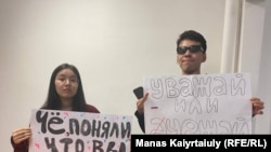 Qaragoz Qasym (left) and Aisultan Qudaibergen were detained at Almaty airport while holding posters saying: "Did you realize that you are cannon fodder?" and "Either respect or go away."