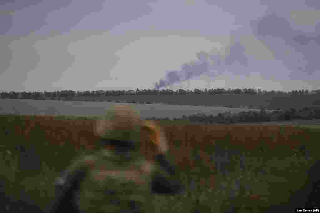 Smoke rises in the distance as a National Guardsman looks on during the operation to retrieve fallen Ukrainians.&nbsp; The mission took place in an unspecified area of the Kharkiv region, near the border with Russia.&nbsp;