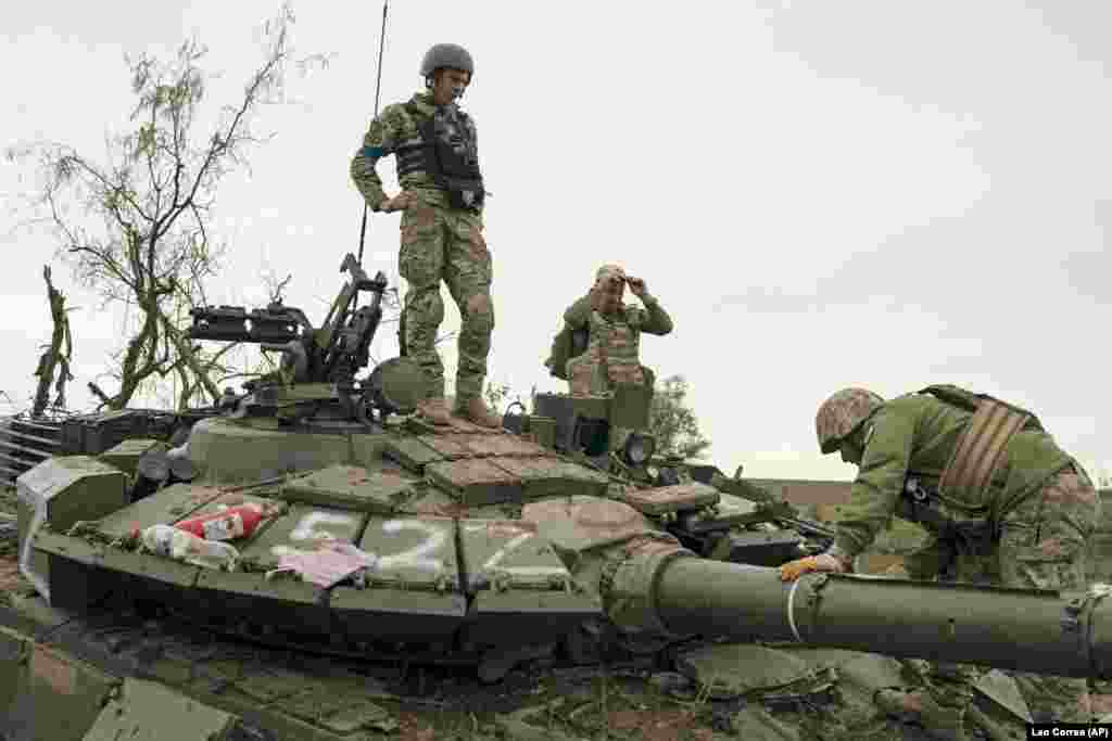 Ukrainian soldiers inspect the damaged Russian tank.&nbsp;