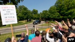 Демонстранты стоят у дороги, по которой проезжают гости Бильдербергской конференции в Лондоне.