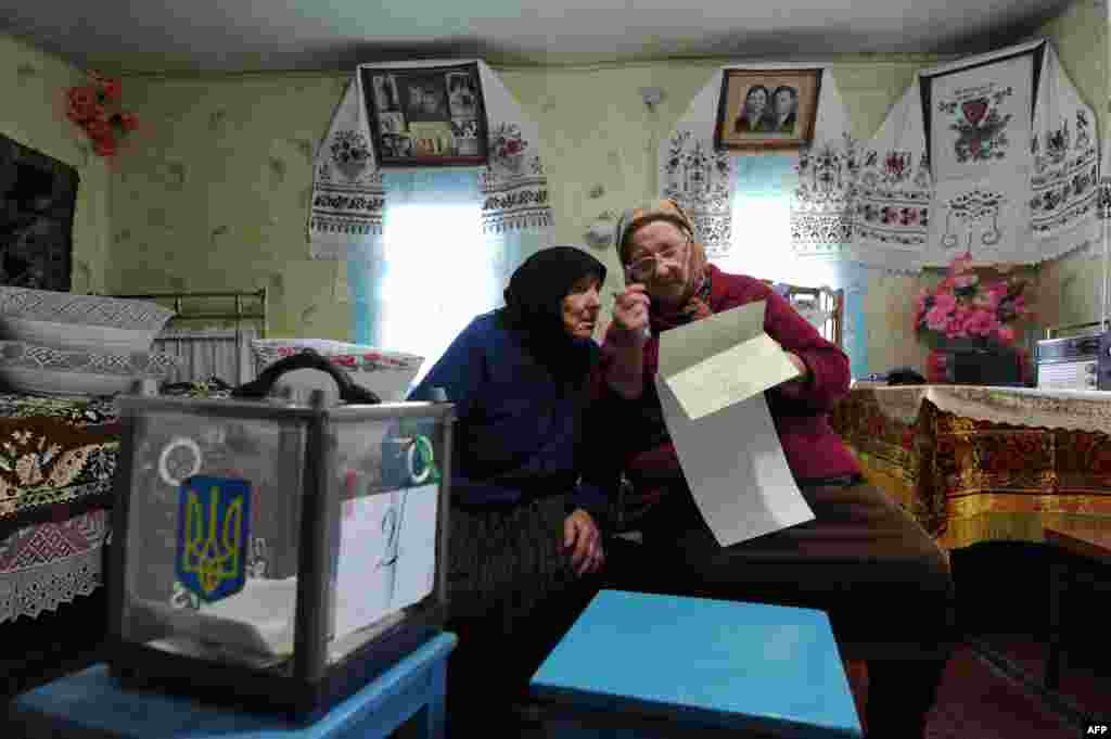 Elderly women check a ballot in the village of Rusaki.