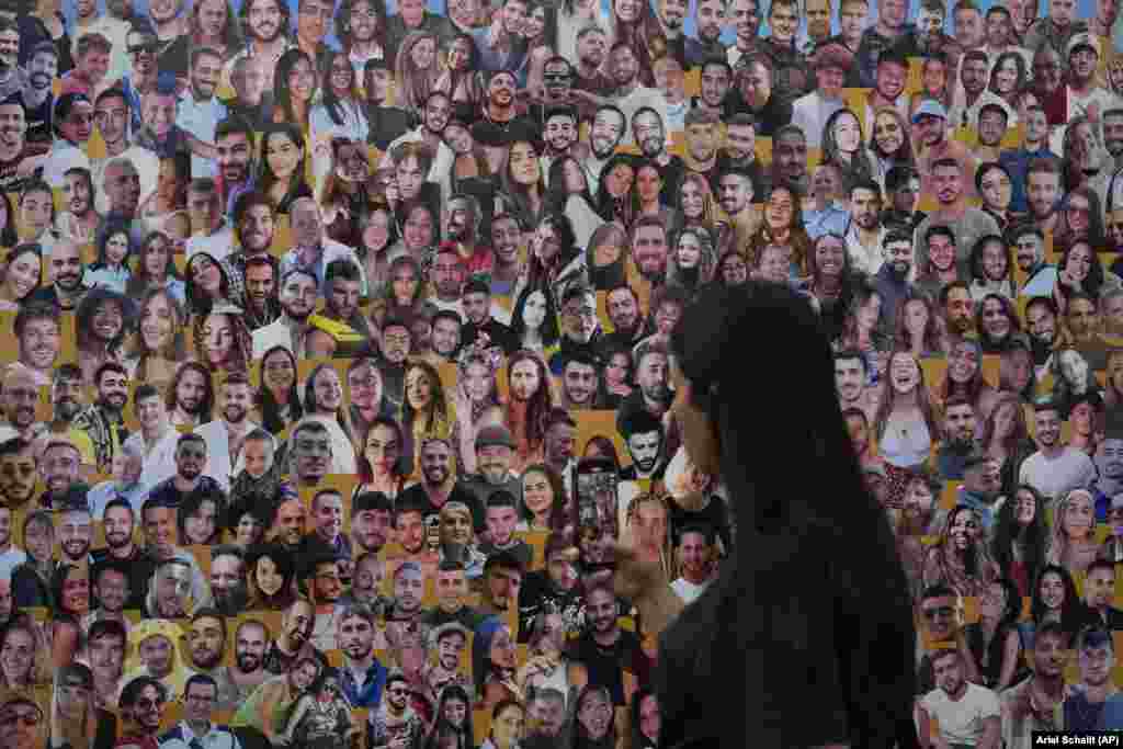 An attendant walks past a mural with portraits of the victims at the site of the Nova music festival on October 7.