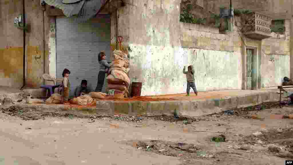 Syrian children hide behind sandbags on the street in the central town of Rastan, near Homs. (AFP)