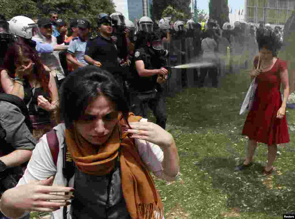 A Turkish riot policeman uses tear gas point-blank against one woman as people protest in Istanbul's Taksim Square against a city development project. (Reuters/Osman Orsal)