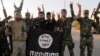 Members of the Hizbullah Brigades flash the victory sign while holding an Islamic State group flag in southern Iraq in October 2014.