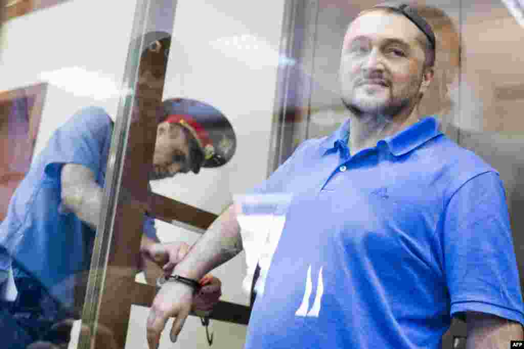 Rustam Makhmudov, who is suspected of gunning down the renowned journalist and Kremlin critic Anna Politkovskaya, stands in a glass cage in a Moscow court. A Russian court has resumed the trial of five men accused of murdering Politkovskaya in 2006, after a long-running investigation that has failed to identify the mastermind behind the crime. (AFP/Evgeny Feldman)