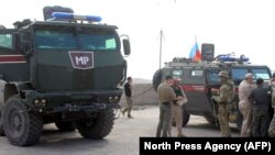 Russian military police troops stand next to their armored vehicles in the northeastern Syrian city of Kobani on October 23.