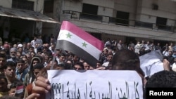 Protesters hold a poster reading: "All cities in Syria are terrorist!???" during a demonstration in the port city of Banias.