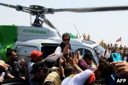 Imran Khan waves to supporters upon arriving on a helicopter to lead a protest rally in Swabai on May 25.