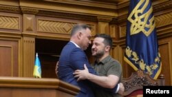 Președintele polonez Andrzej Duda îl îmbrățișează pe președintele ucrainean Volodimir Zelenski în timpul unei ședințe a parlamentului de la Kiev, pe 22 mai 2022. 