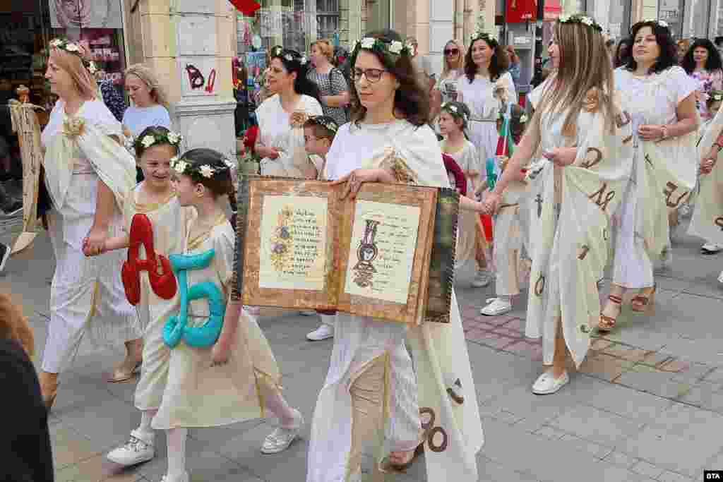 Locals of Ruse in northern Bulgaria wear gowns featuring Cyrillic characters.&nbsp; Bulgarians turned out en masse on May 24 to honor the legacy of Saints Cyril and Methodius during a holiday named after the two brothers.