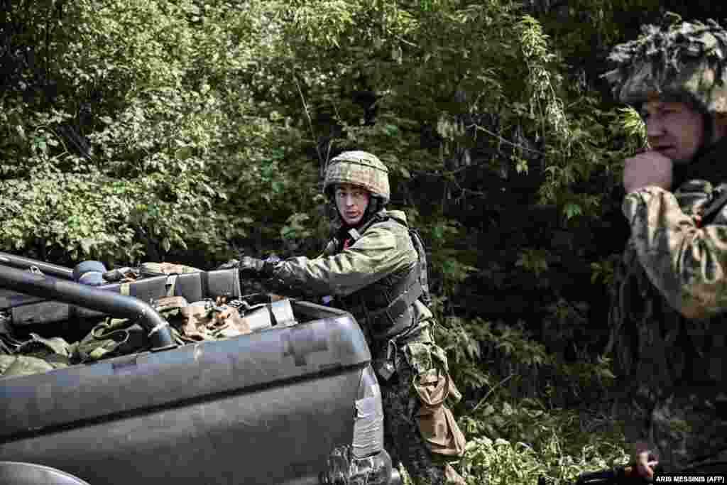 Ukrainian servicemen prepare their equipment before moving toward the front line.