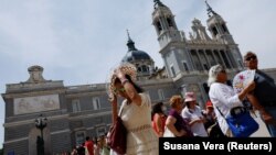 Turisti koriste lepeze i šešire kako bi se zaštitili od sunca ispred katedrale La Almudena u Madridu, 21. maj 2022.