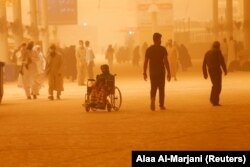 Emberek egy homokvihar idején az iraki Nadzsafban, 2022. május 23-án.