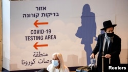 Utasok a csomagjaikkal a Tel-Aviv melletti Ben Gurion repülőtéren, a delta-variáns terjedése közepette, 2021. július 8-án 