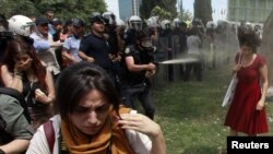 Turkey - A Turkish riot policeman uses tear gas as people protest against the destruction of trees in a park brought about by a pedestrian project, in Taksim Square in central Istanbul, 28May2013