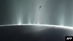 Sonda e NASA-s, Cassini (një pikë e zezë në pjesën e sipërme), duke lëvizur nëpër tufat e Enceladusit, që është hëna e Saturnit, në vitin 2015