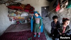 Internally displaced Afghan children stand inside their shelter at a refugee camp in Kabul.