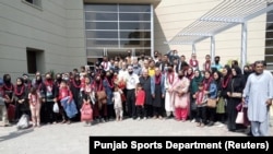 A previous group of evacuated Afghan female soccer players along with their families pose for a group photo upon their arrival in Lahore on September 15.