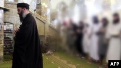 A video grab allegedly shows the leader of the Islamic State (IS) jihadist group, Abu Bakr al-Baghdadi, leading prayers next to machine guns with Muslim worshippers behind him.